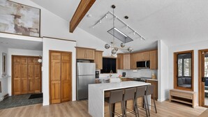 A modern kitchen with wooden cabinets, stainless steel appliances, and a bar area with stools. - Luxury 5BR Poconos Retreat | Ski, Lake & Resort (Saw Creek)