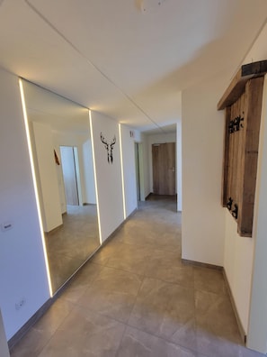Ein Flur mit einem großen Spiegel, einem Holzschrank und einer Dekoration mit einem Hirschkopf.