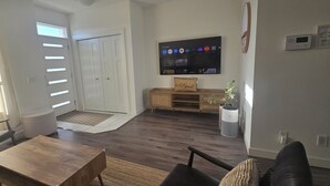 Ein Wohnzimmer mit Fernseher, Sofa, Couchtisch und einer Tür zu einem anderen Raum.
