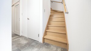 A staircase with wooden steps and a handrail, leading to a white door. - Farandole Sanno (Osaka)