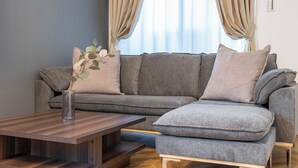 A modern living room with a grey sectional sofa, a wooden coffee table, and a vase with a plant. - Farandole Sanno (Osaka)
