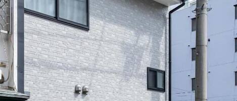 A modern building with a grey brick facade, a door, and a small window.