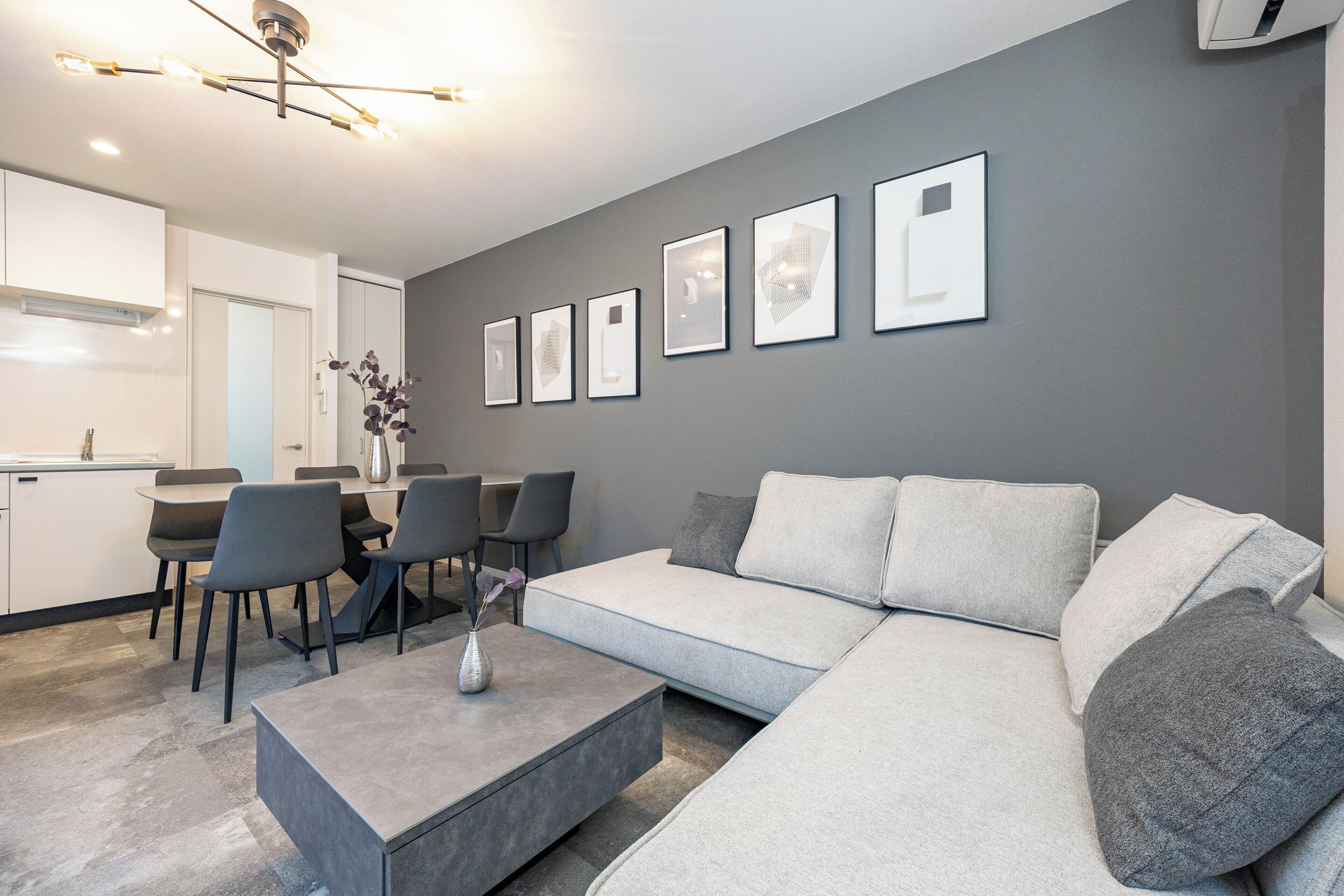 Una sala moderna con un sofá gris, una mesa de centro y un comedor con sillas y una mesa.