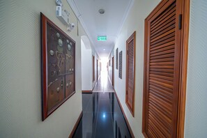 A hotel hallway with a polished black floor, wooden doors, and framed artwork on the walls. - Viewtalay Longstay (Pattaya)
