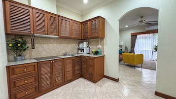 A modern kitchen with wooden cabinets, a built-in microwave, and a potted plant.
