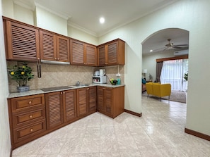 Una cocina moderna con armarios de madera, un microondas integrado y una planta en maceta.
