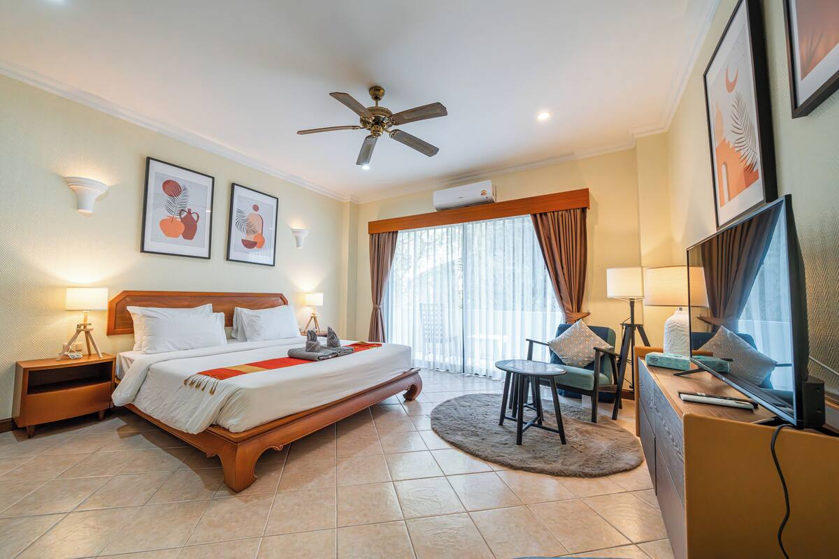 Une chambre d’hôtel avec un grand lit, un ventilateur de plafond, une télévision, un bureau et une chaise.