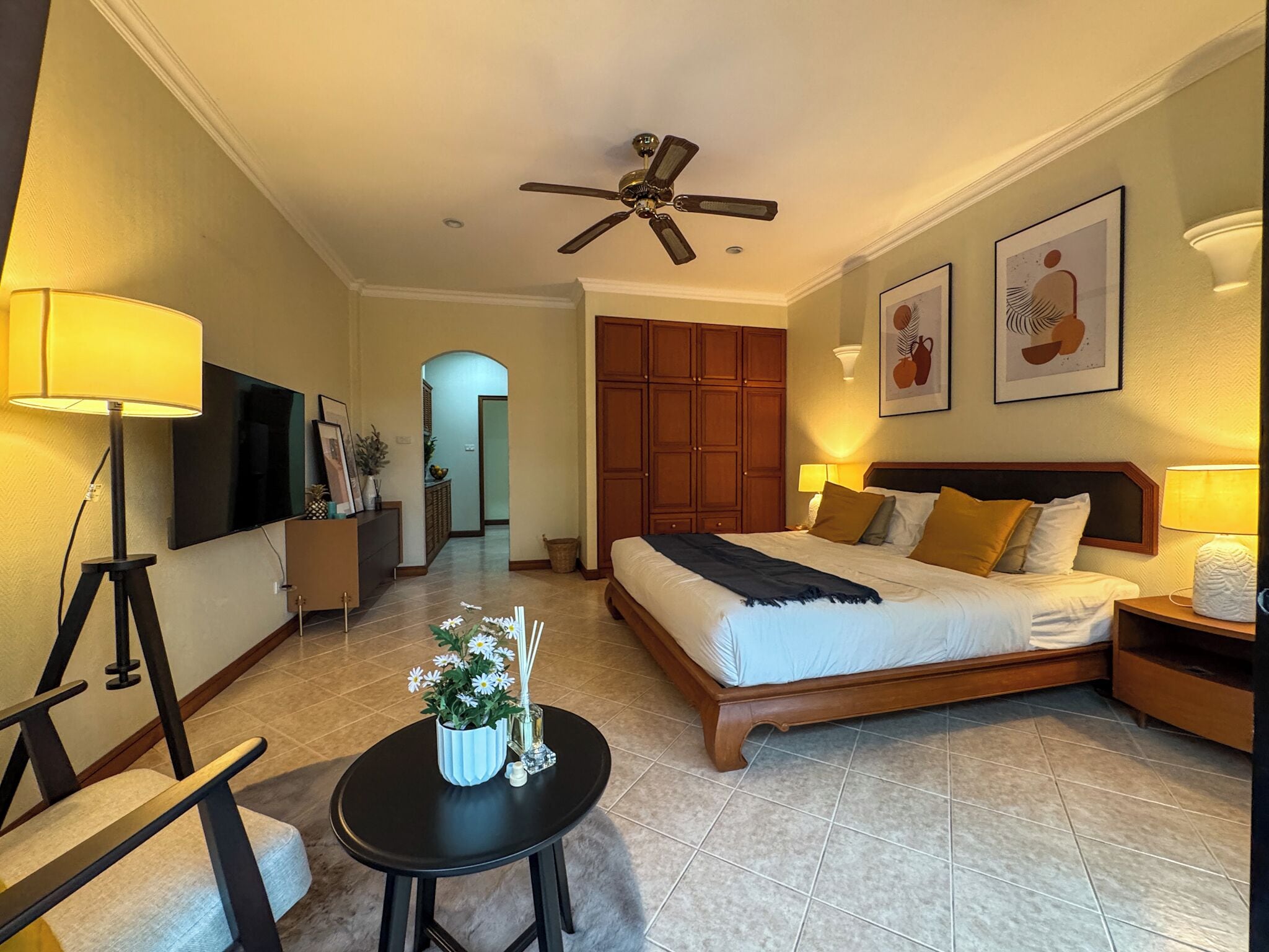 Une chambre d’hôtel équipée d’un lit, d’un ventilateur de plafond, d’une télévision, d’un bureau et d’une chaise.