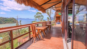A wooden deck with tables and chairs overlooking a scenic view.