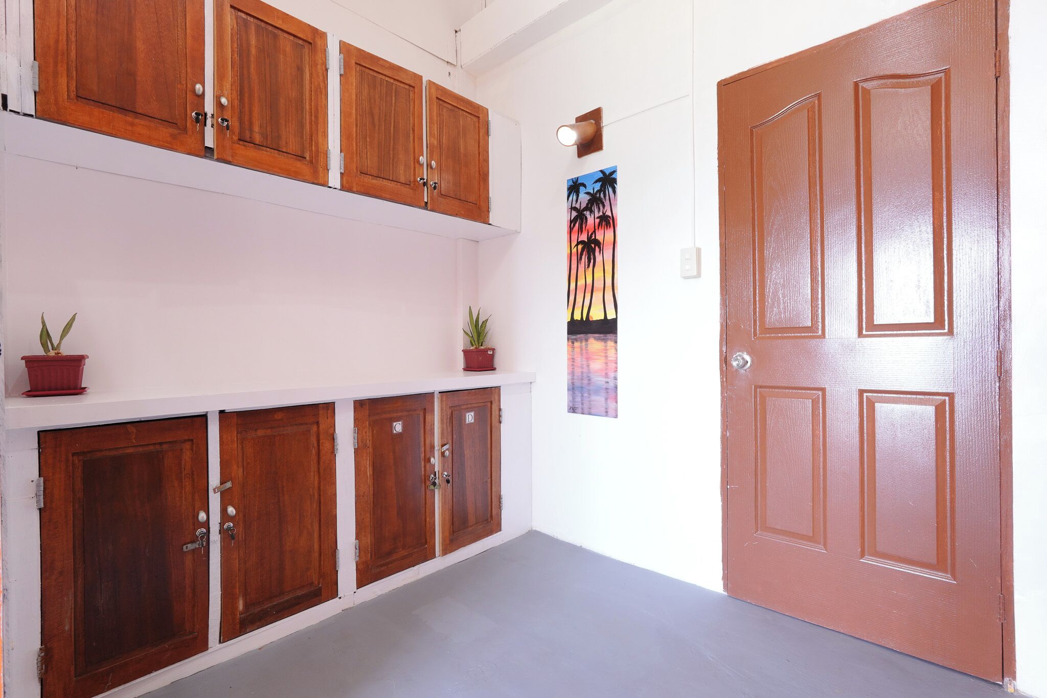 A hallway with wooden cabinets, a door, and a wall-mounted light fixture.