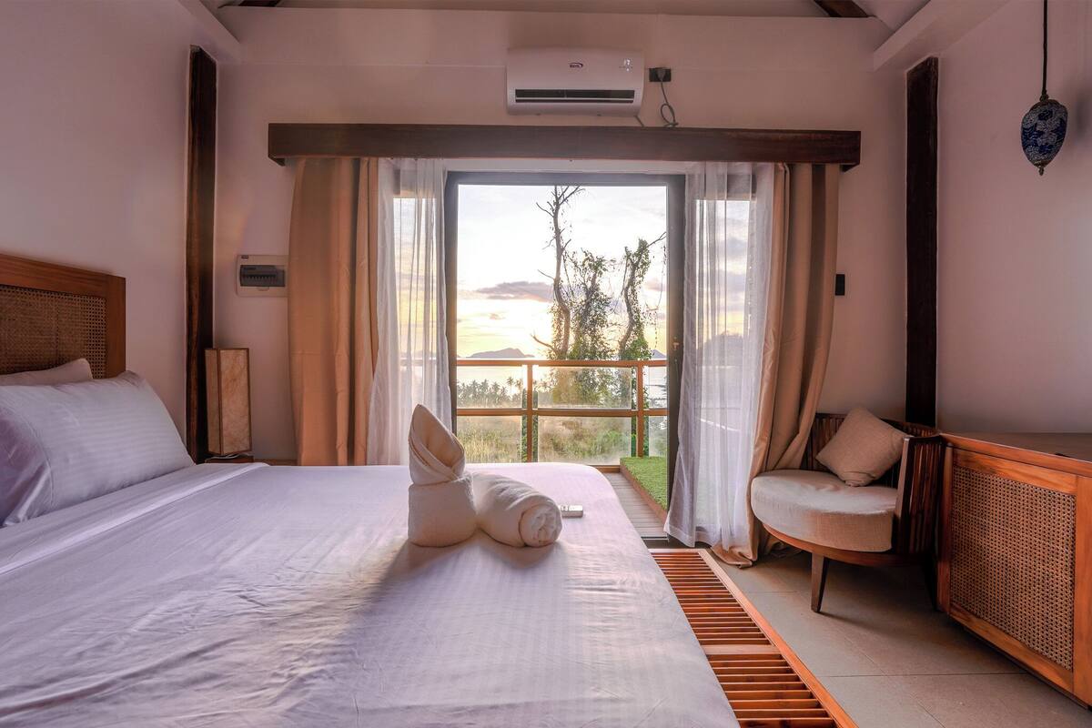 Ein Hotelzimmer mit einem Bett, einem Sessel, einem Fenster mit Vorhängen und einer Klimaanlage.