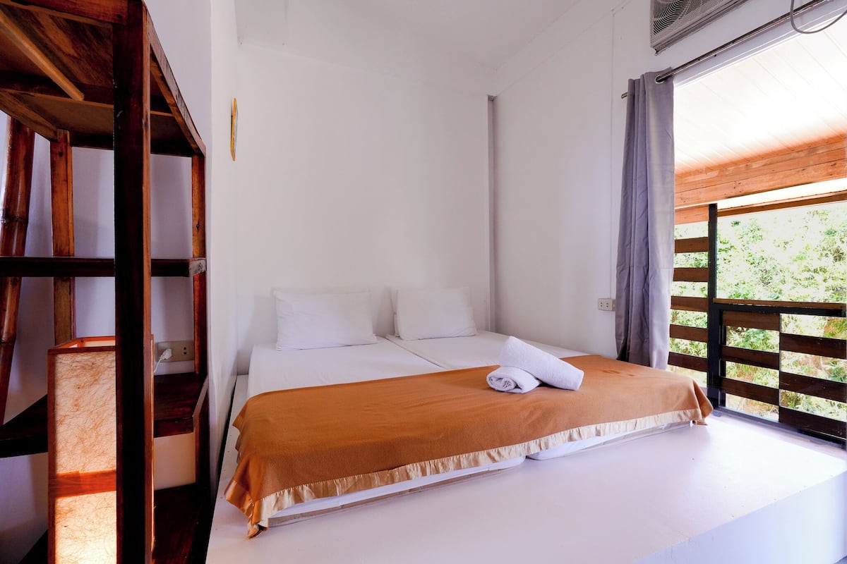 Ein Schlafzimmer mit einem Bett, einem Holzregal und einem Fenster mit Blick.