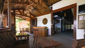A wooden interior with a reception desk, seating area, and a staircase.