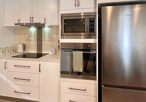 A modern kitchen with stainless steel appliances, including a microwave, oven, and refrigerator. - Cambridge Opening Special prices, enjoy the newness (Mornington)