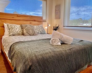 A neatly made bed with patterned pillows, a rolled towel, and a view of the outdoors through a window. - Cambridge Opening Special prices, enjoy the newness (Mornington)