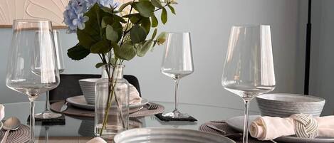 A dining table set with plates, glasses, and a vase with flowers.