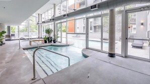 A modern indoor pool area with clear glass walls, a concrete floor, and a few potted plants. - 29th Floor Condo in Yaletown. Message me at a.hostacny@gmail.com for details 
 (Vancouver)
