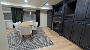 Zona pranzo con tavolo rotondo in legno e sedie, tappeto decorato e pensili in legno scuro.