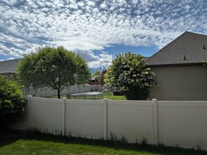 A residential area with a white fence, trees, and a clear sky. - Cozy 3BR private basement unit by SF River trail in Spanish Fork (Spanish Fork)