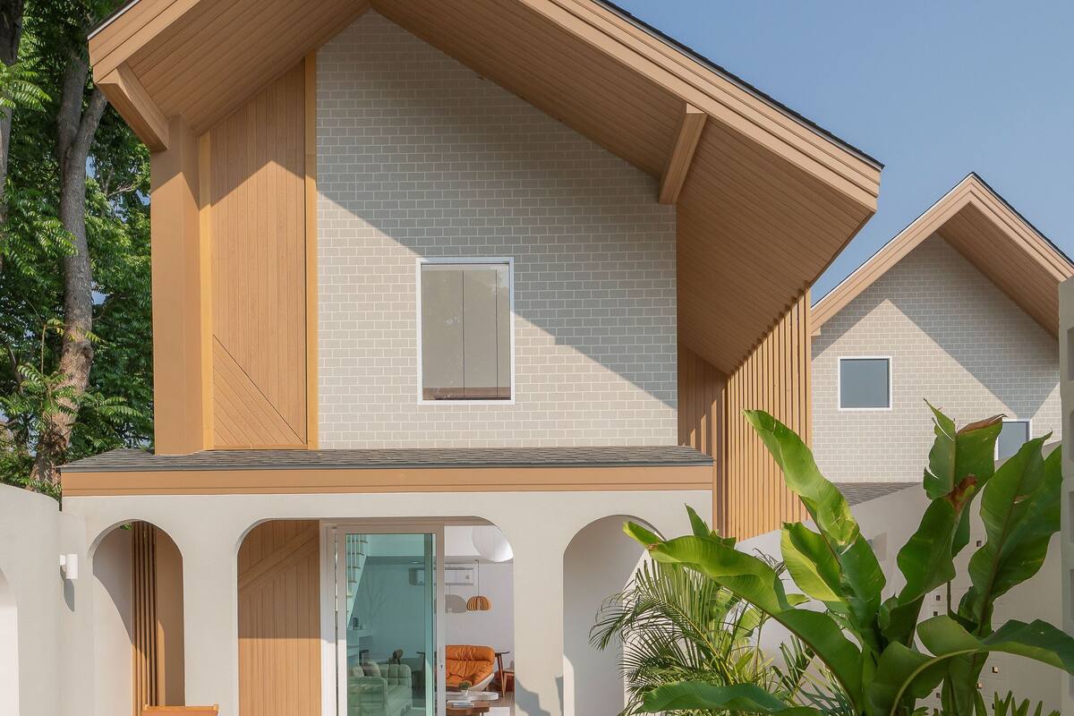 Una casa moderna con piscina, terraza de madera y plantas tropicales.