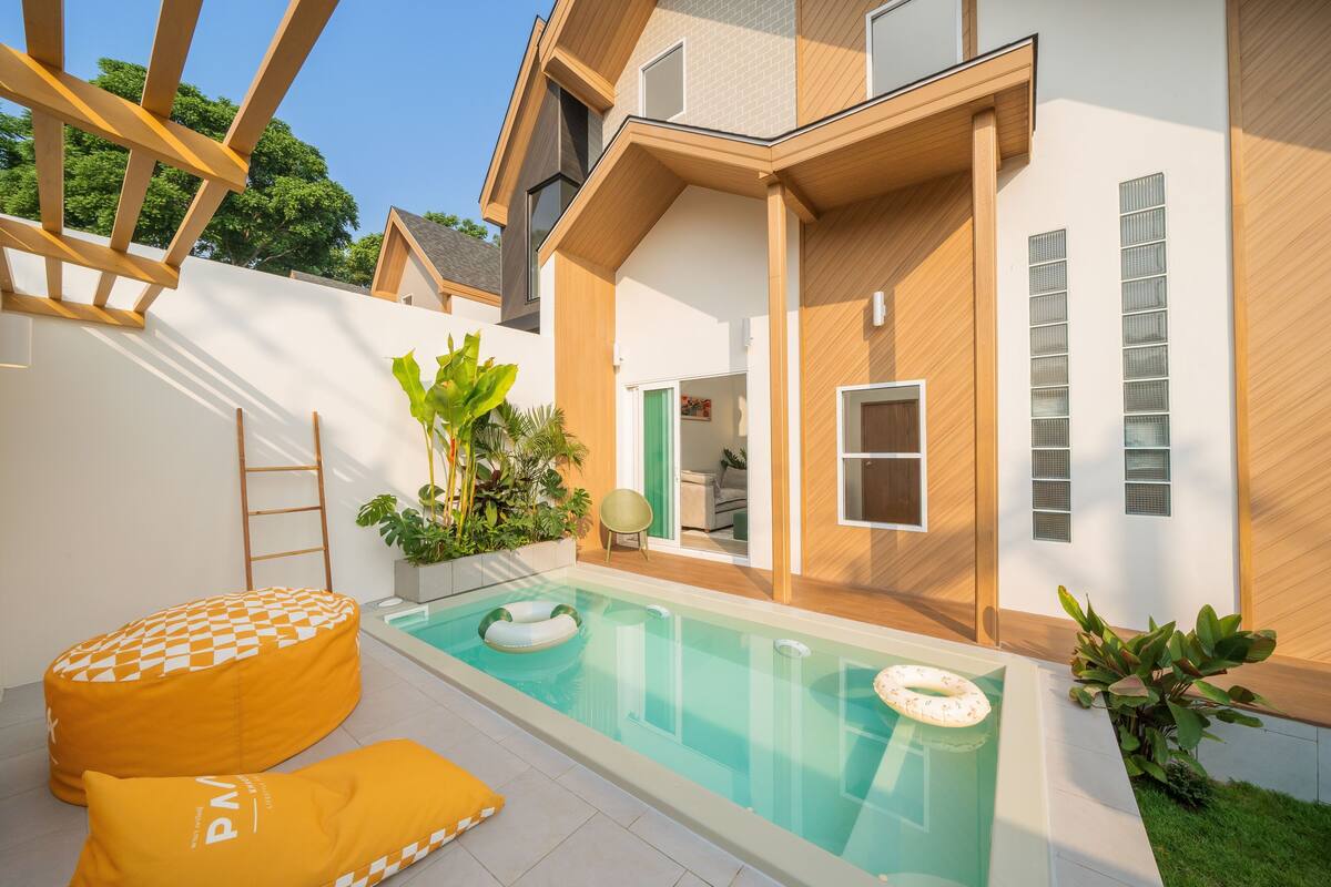 Una casa moderna con piscina, mobiliario exterior y terraza de madera.