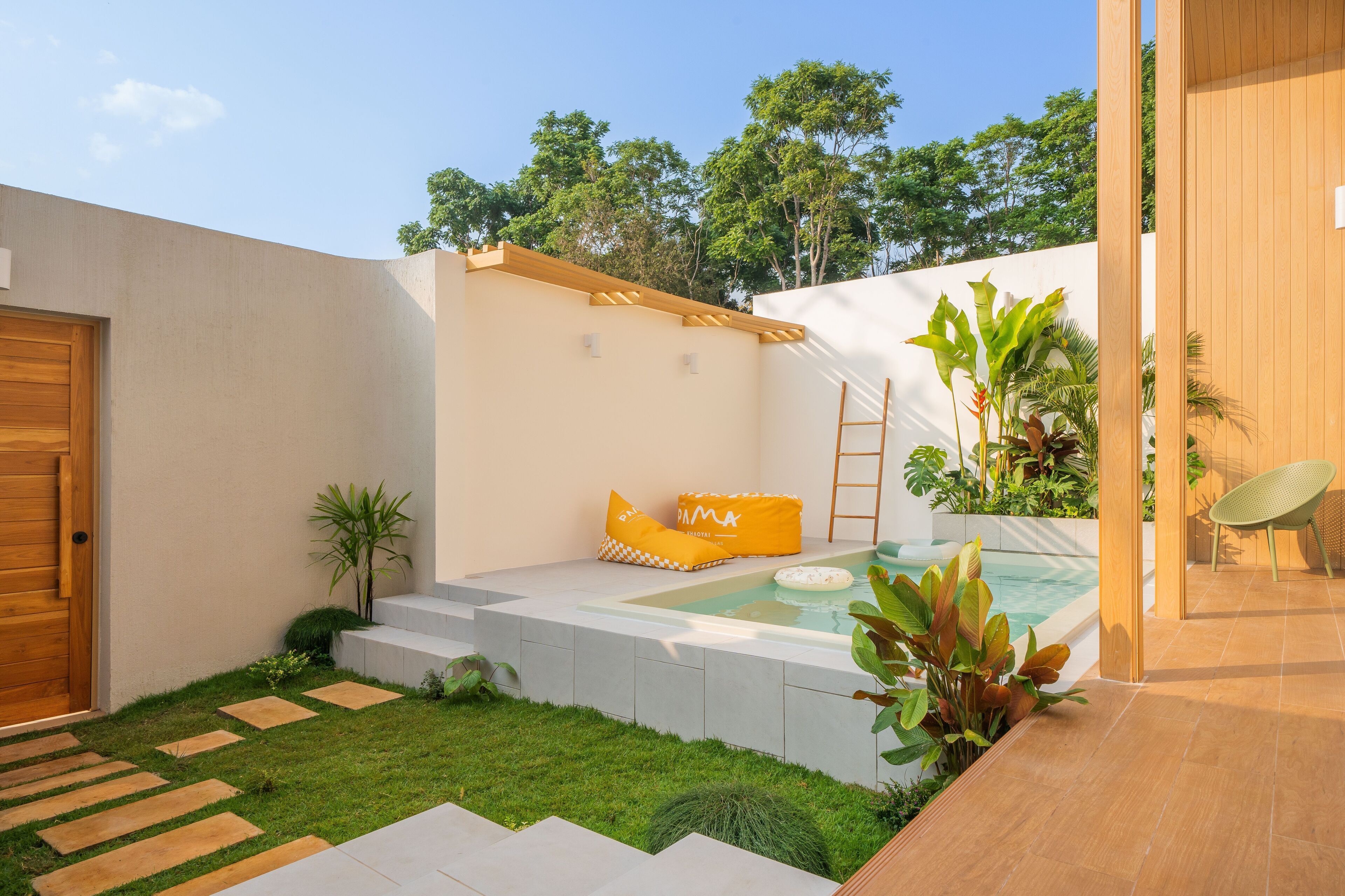 A modern outdoor patio with a hot tub, a wooden door, and a seating area with cushions.