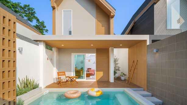 Une maison moderne dotée d’une piscine, d’un espace salon extérieur et d’une terrasse en bois.