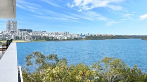 Une vue sur le front de mer, avec des bâtiments modernes, un ciel dégagé et une étendue d’eau calme.