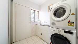 A compact laundry room with a washing machine, a dryer, and a sink. - Room for Everyone Spacious 4BR Pool Retreat (Kirwan)