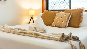 A neatly made bed with a rolled white towel, two patterned pillows, and a beige throw blanket. - Room for Everyone Spacious 4BR Pool Retreat (Kirwan)