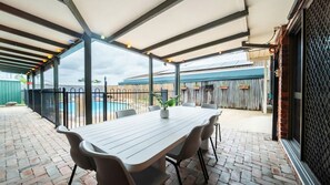 Un'area patio coperta con piscina, posti a sedere all'aperto e vista sulla piscina.