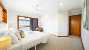 A hotel room with a bed, a chair, a desk, a ceiling fan, and a view of the outdoors. - Room for Everyone Spacious 4BR Pool Retreat (Kirwan)
