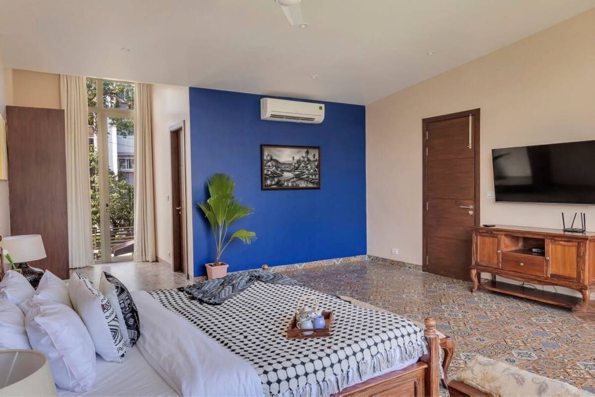 Ein Hotelzimmer mit Bett, Fernseher, Blumentopf und einem Bild an der Wand.