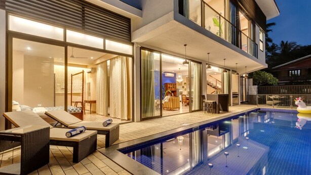 Een modern huis met een zwembad, grote glazen deuren en een terras.