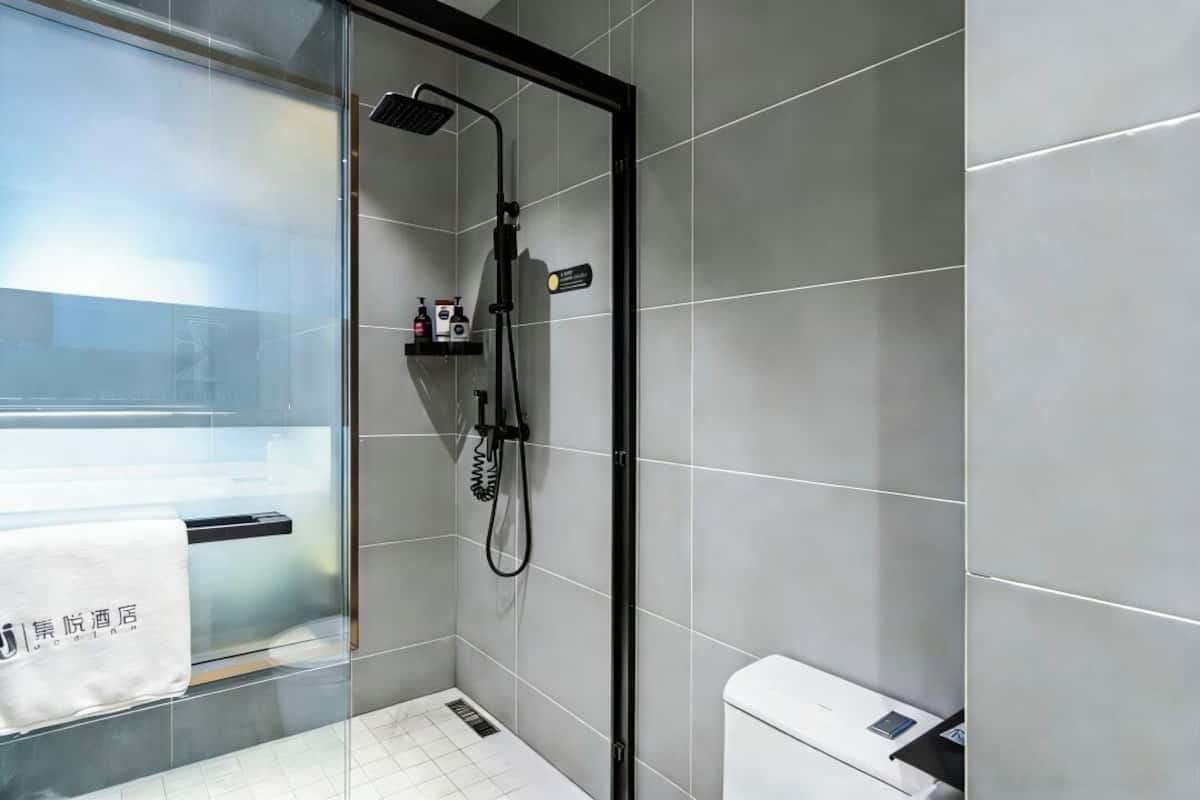 A modern bathroom with a glass shower enclosure, a white sink, and a towel rack with a towel.