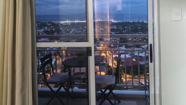 A balcony with a city view, a table, and chairs. - 1517 Belvedere Samal View and City View (Davao City)