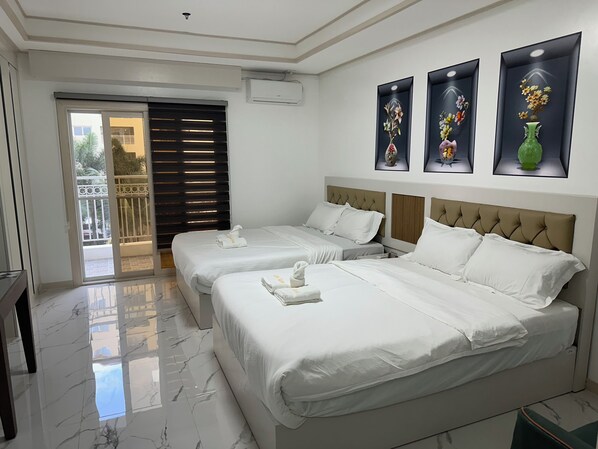 Une chambre d’hôtel avec deux lits, un balcon et trois œuvres d’art florales encadrées accrochées au mur.