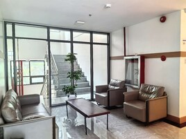 Un salón amplio con un gran ventanal, una escalera y una disposición de asientos que incluye un sofá y sillones.