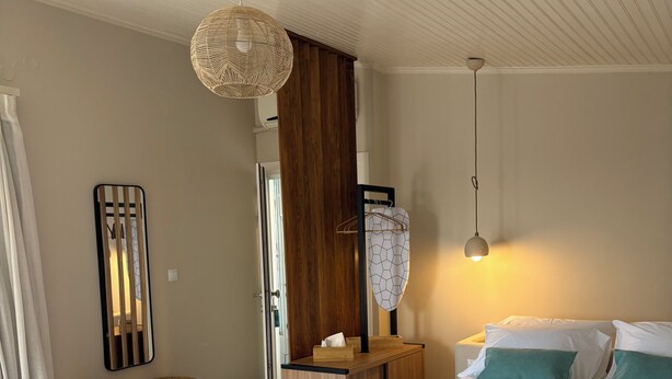 Ein modernes Schlafzimmer mit einem großen Bett, einer hölzernen Bank, einem Spiegel und einer Pendelleuchte.