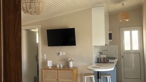 Eine moderne Küche mit Flachbildfernseher, Holzschränken und einer Bar mit Hockern.