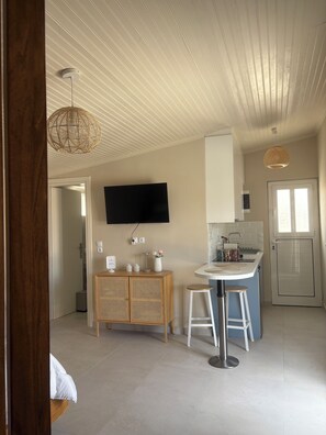 A modern kitchen with a flat-screen TV, wooden cabinets, and a bar area with stools. - Enjoy the slow living in beautiful Gythio (Githio)