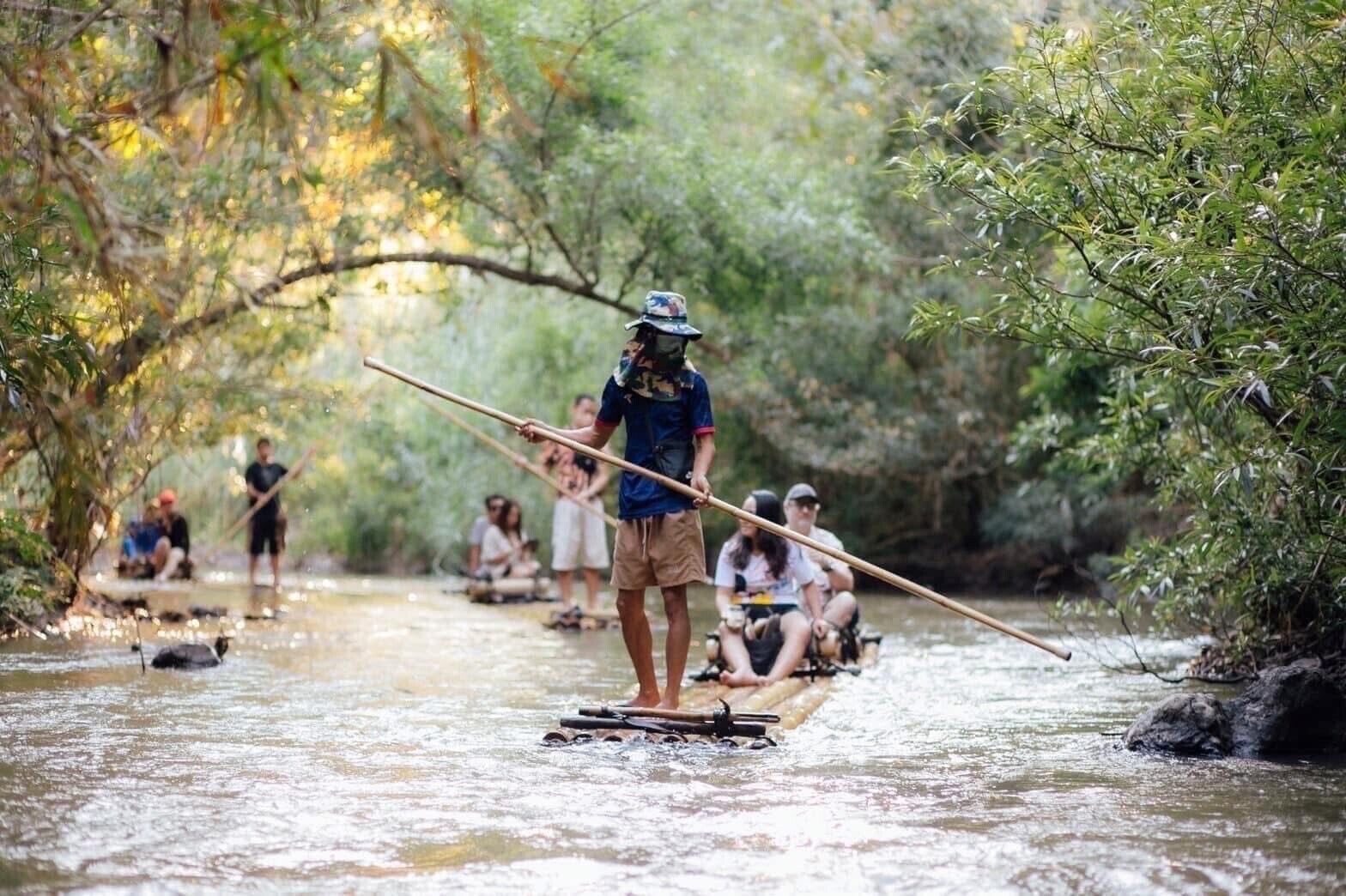 A river scene with people paddling on a narrow waterway surrounded by dense foliage.