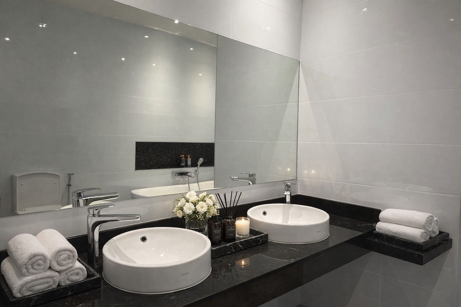 Un baño moderno con dos lavamanos, un espejo grande y una encimera negra.