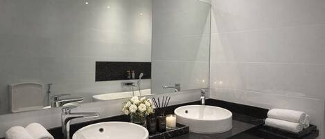Un baño moderno con dos lavamanos, un espejo grande y una encimera negra.