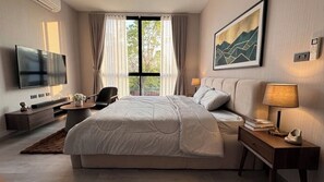 Une chambre d’hôtel moderne, dotée d’un grand lit, d’une télévision à écran plat, d’un bureau avec une lampe et d’un tableau au mur.
