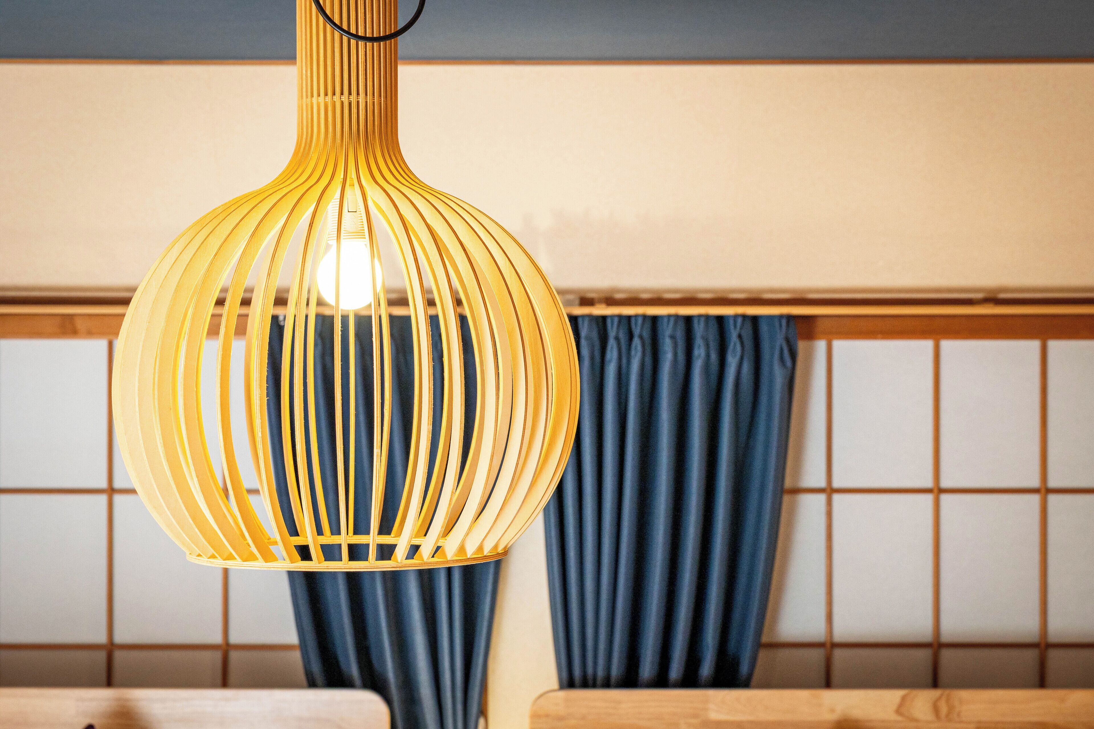 Una lámpara colgante amarilla de diseño acanalado en una habitación con muebles de madera y cortinas azules.