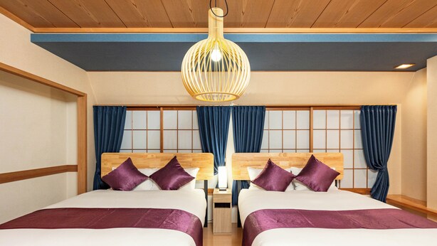 A hotel room with two beds, wooden headboards, purple bedding, a hanging light fixture, and a traditional Japanese shoji screen behind the beds. - Loger Tengachaya (Osaka)