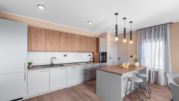 A modern kitchen with wooden cabinets, a central island with bar stools, and pendant lighting. - Apartment Near Beach With sea View (Porec)