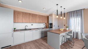 A modern kitchen with wooden cabinets, a central island with stools, and pendant lighting. - Apartment Near Beach With sea View (Porec)