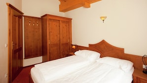 A bedroom with a wooden bed, a nightstand, and a wardrobe. - Chalet in Saalbach Near Ski Lift (Saalbach-Hinterglemm)